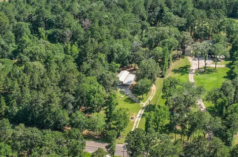 an aerial view of residential house with outdoor space and trees all around