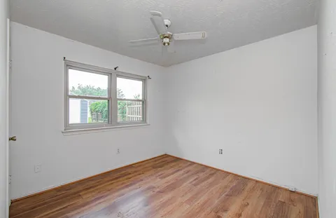 an empty room with a window and a ceiling fan