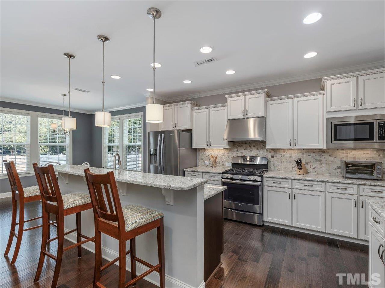 604 Chapanoke Road Raleigh, NC 27603 - Photo 2 of 30 a kitchen with stainless steel appliances granite countertop a stove a sink a microwave a island with a dining table and chairs