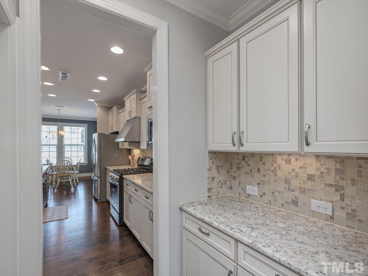 604 Chapanoke Road Raleigh, NC 27603 - Photo 4 of 30 a kitchen with stainless steel appliances granite countertop a stove top oven a sink a dining table and chairs with wooden floor