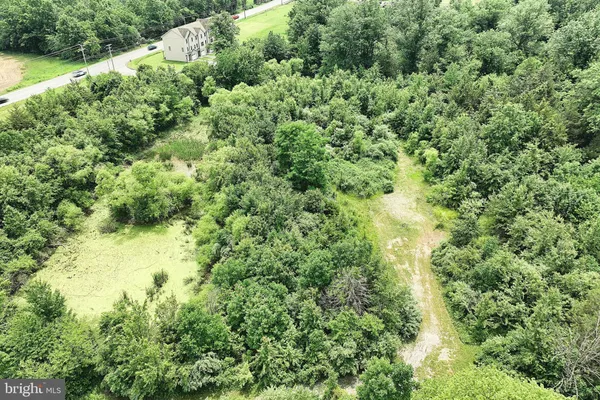 an aerial view of residential house with outdoor space and trees all around