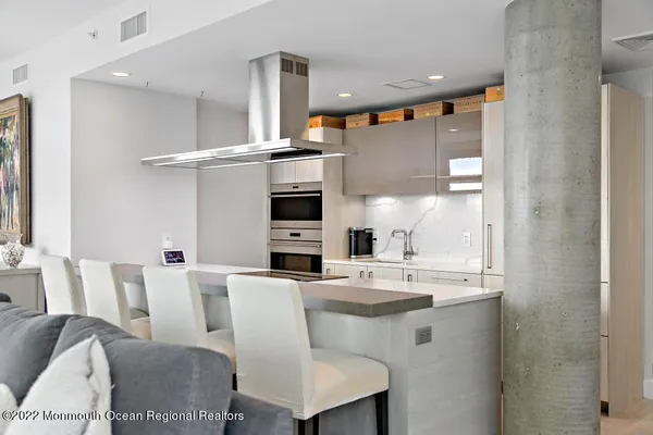 a kitchen with stainless steel appliances kitchen island granite countertop a table chairs in it and wooden floors