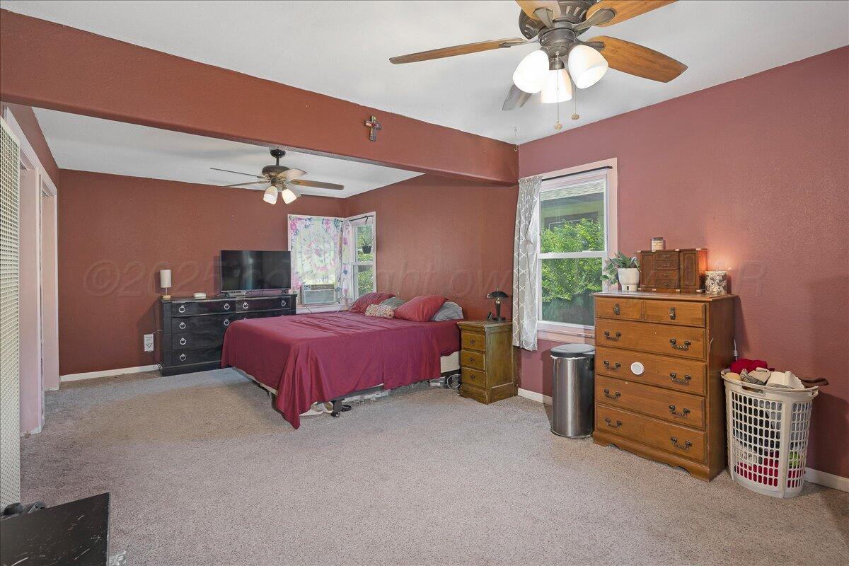 4317 Cline Road Amarillo, TX 79110 - Photo 9 of 18 a spacious bedroom with a bed and a chandelier