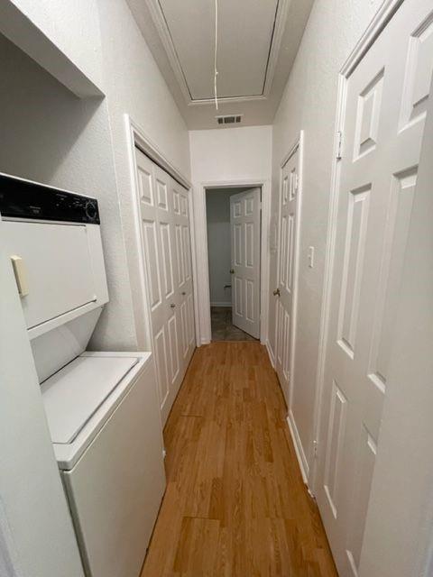 2529 Rio Grande Street, Unit 64 Austin, TX 78705 - Photo 6 of 9 Corridor with attic access, light wood-type flooring, and stacked washer and clothes dryer