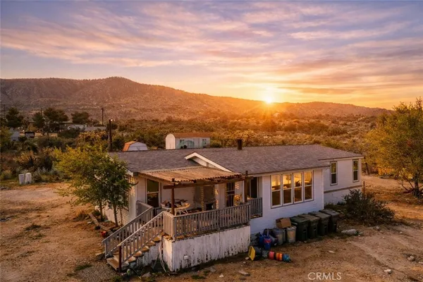 an aerial view of residential houses with a yard and mountain view in back