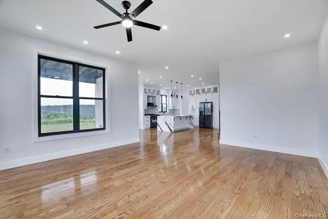 a view of empty room with wooden floor and window