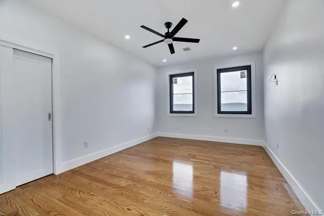 a view of empty room with wooden floor and ceiling fan
