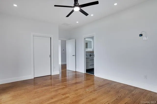 a view of empty room with wooden floor and ceiling fan