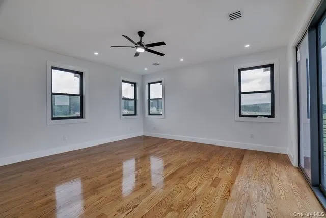 a view of empty room with wooden floor and fan
