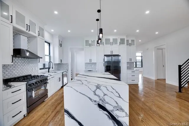 a large kitchen with stainless steel appliances kitchen island granite countertop a stove a refrigerator a oven and a sink