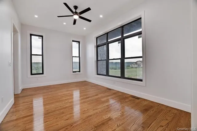 a view of an empty room with a window and wooden floor