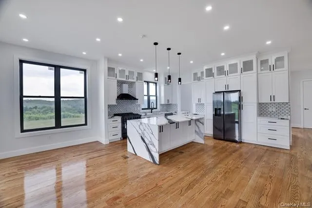 a large living room with stainless steel appliances furniture a large window and a chandelier