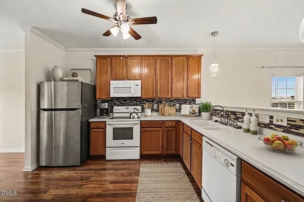 a kitchen with a refrigerator a stove a sink and dishwasher with wooden floor