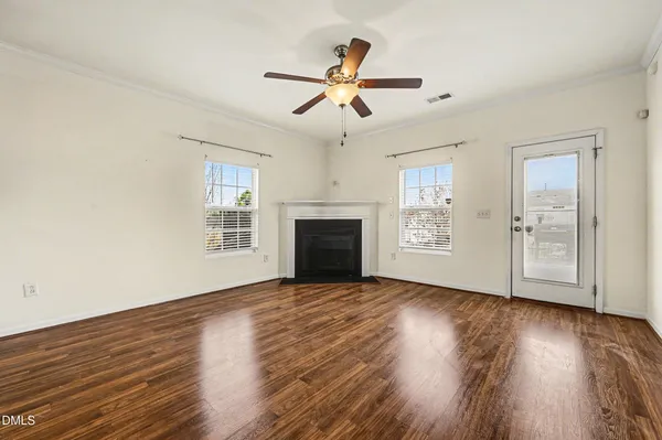 a view of an empty room with wooden floor fireplace and a window