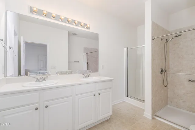 a bathroom with a double vanity sink mirror and shower