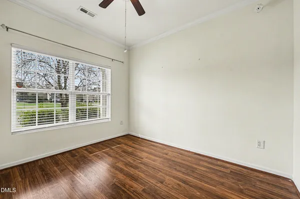 a view of an empty room with wooden floor and a window
