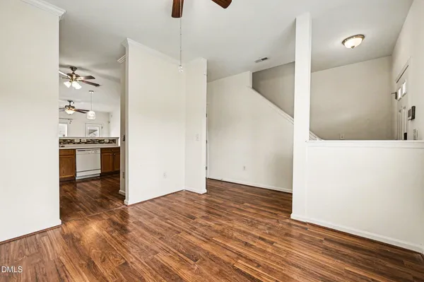 a view of kitchen and empty room with wooden floor
