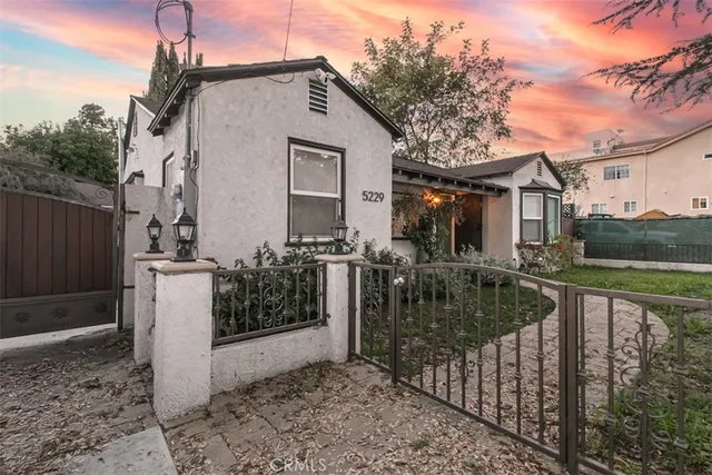 a view of a house and yard with wooden fence