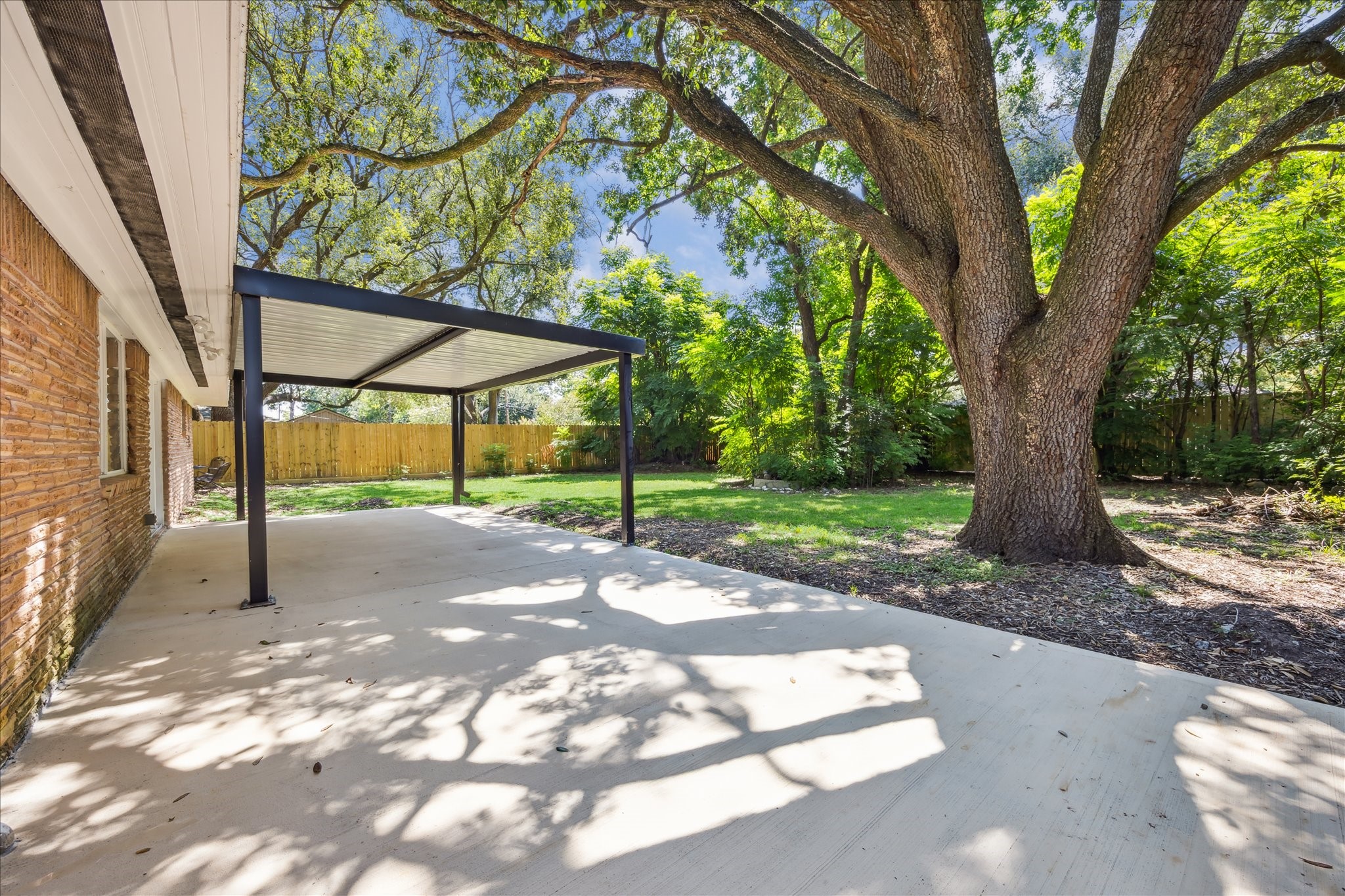 5419 Beechnut Street Houston, TX 77096 - Photo 23 of 28 Expansive covered patio overlooking a lush backyard, shaded by gorgeous mature trees, ideal for relaxing or entertaining.