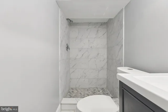 a bathroom with a granite countertop toilet sink and mirror