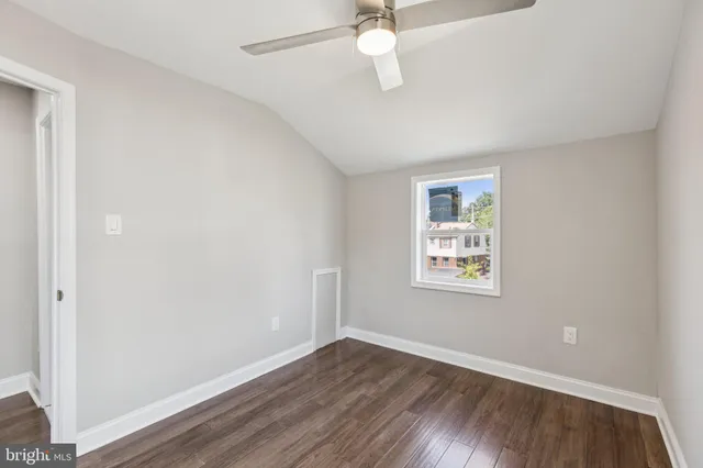 an empty room with wooden floor chandelier fan and windows