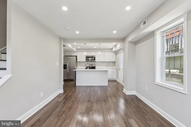 a view of a kitchen with kitchen island stainless steel appliances wooden floor and window
