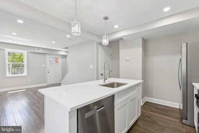 a kitchen with a sink a center island and wooden floor