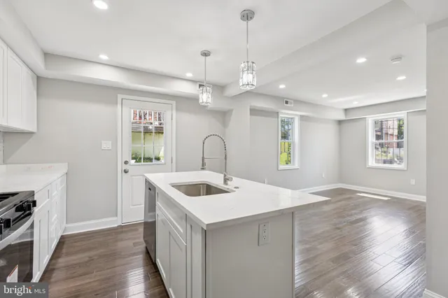a kitchen with kitchen island a sink stainless steel appliances and wooden floor