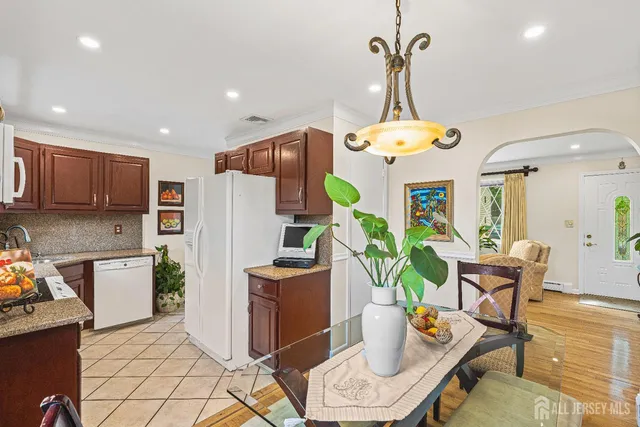 a kitchen with stainless steel appliances granite countertop a refrigerator a sink a stove a dining table and chairs with wooden floor