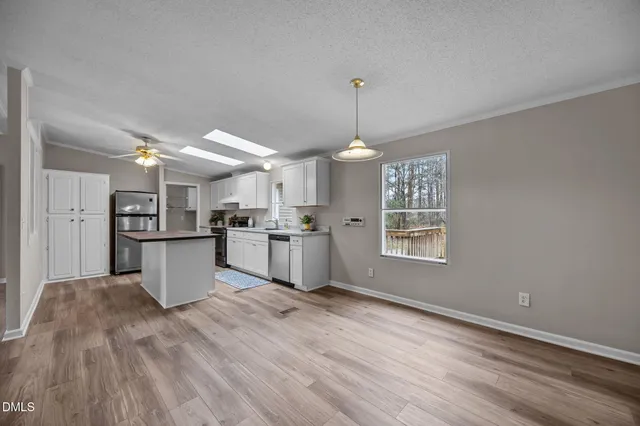 a kitchen with stainless steel appliances kitchen island hardwood floor sink stove and wooden cabinets