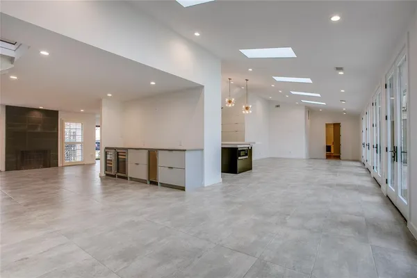 a view of an empty room with kitchen view and a sink