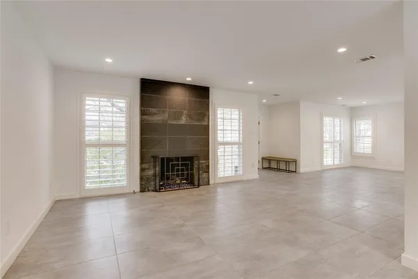 an empty room with windows and fireplace
