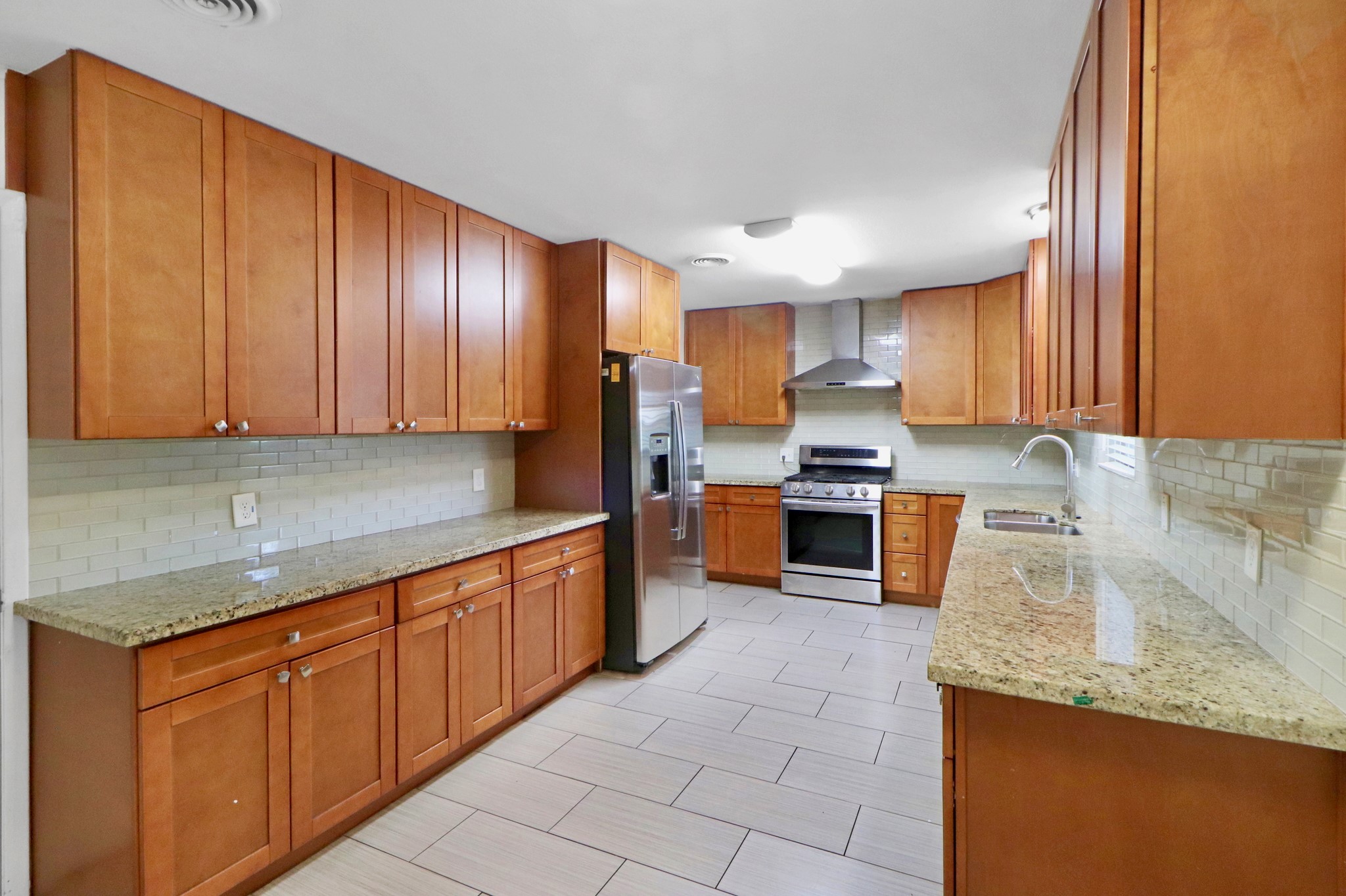 5554 Beechnut Street Houston, TX 77096 - Photo 8 of 30 a kitchen with granite countertop wooden cabinets and stainless steel appliances