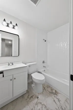 a bathroom with a toilet sink double vanity and tub
