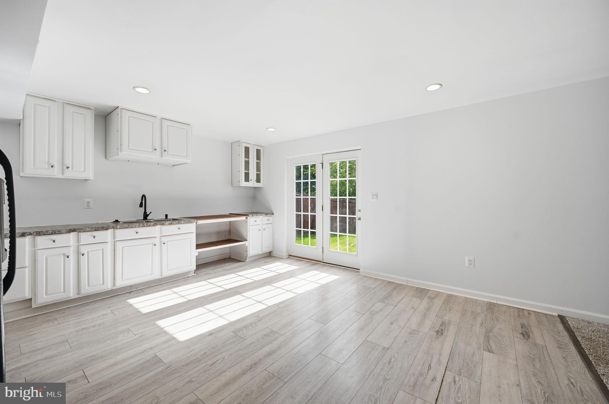687 Blossom Tree Road Culpeper, VA 22701 - Photo 25 of 31 a kitchen with granite countertop a stove a sink and white cabinets with wooden floor next to windows