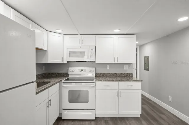 a kitchen with granite countertop white cabinets and white appliances