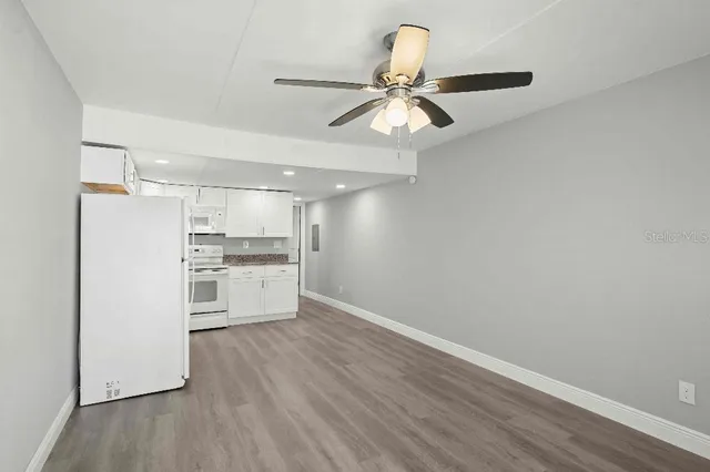 a view of a kitchen with wooden floor electronic appliances and a window