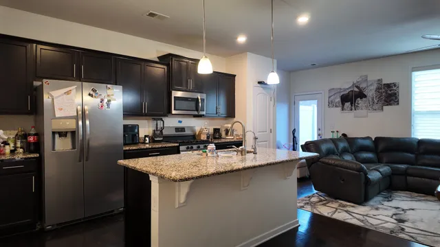 a kitchen with stainless steel appliances granite countertop a refrigerator a sink a stove a microwave a refrigerator and cabinets