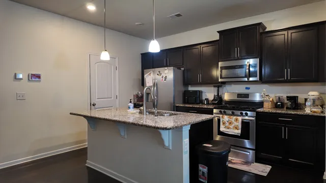 a kitchen with stainless steel appliances granite countertop a sink a stove and refrigerator