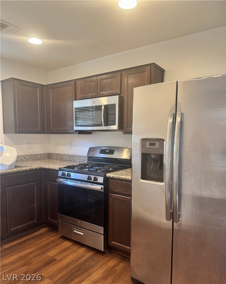 1892 Via Del Rey Court Las Vegas, NV 89115 - Photo 3 of 10 A corner kitchen showcases dark wood cabinetry, granite counters, and modern stainless steel appliances.