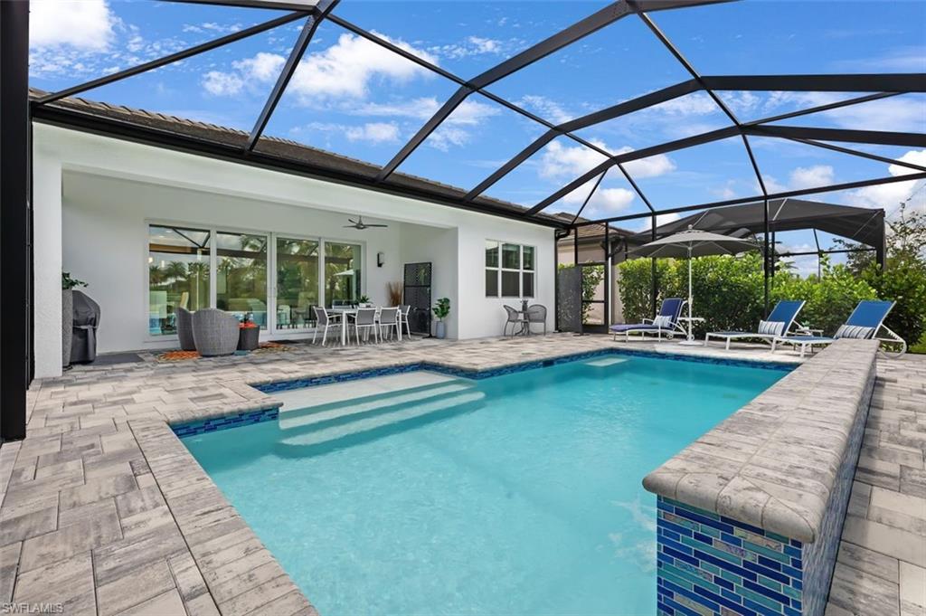 11311 Jacaranda Drive Naples, FL 34120 - Photo 3 of 50 a view of a backyard with swimming pool table and chairs under an umbrella