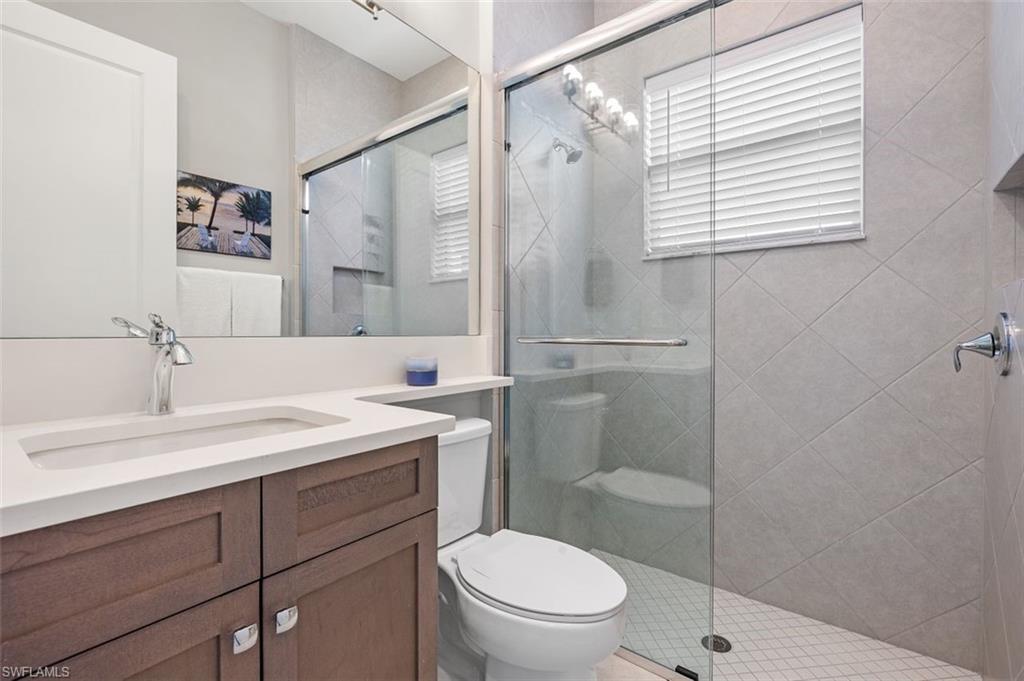 11311 Jacaranda Drive Naples, FL 34120 - Photo 31 of 50 a bathroom with a granite countertop sink toilet a mirror and shower