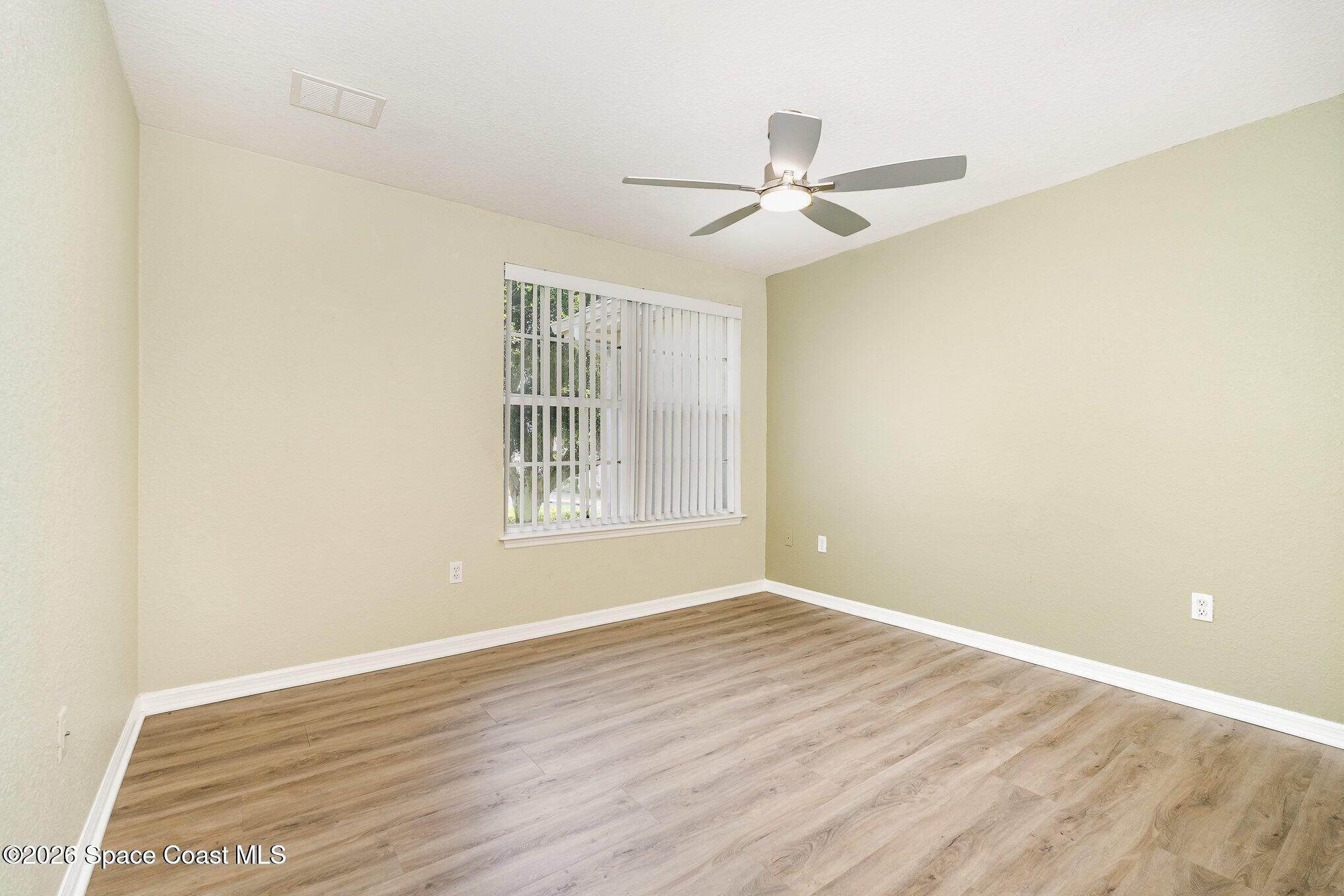110 Colibri Way, Unit 106 Melbourne, FL 32901 - Photo 16 of 28 an empty room with wooden floor fan and windows