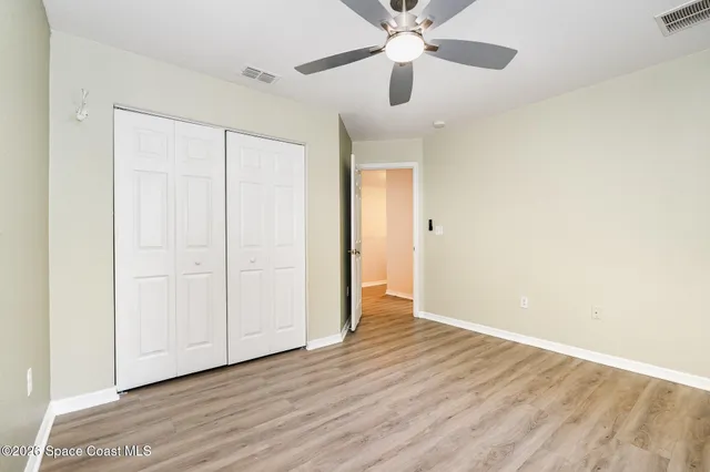 an empty room with wooden floor chandelier fan and closet area