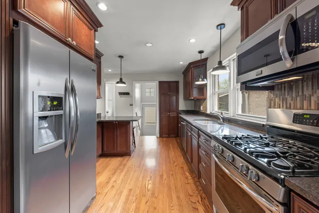 a kitchen with stainless steel appliances granite countertop a stove a refrigerator and a wooden cabinets