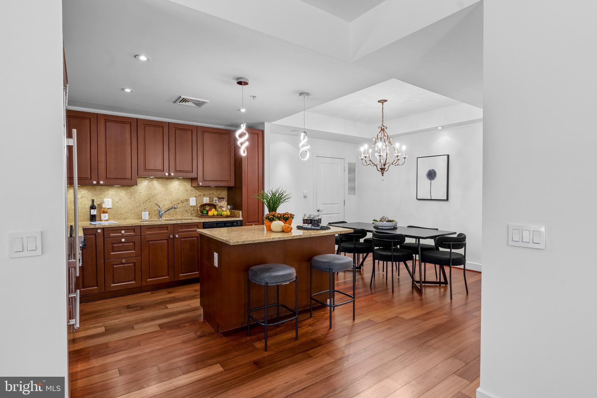 2425 L Street Northwest, Unit 431 Washington, DC 20037 - Photo 13 of 29 a kitchen with stainless steel appliances granite countertop a refrigerator a sink dishwasher a dining table and chairs with wooden floor