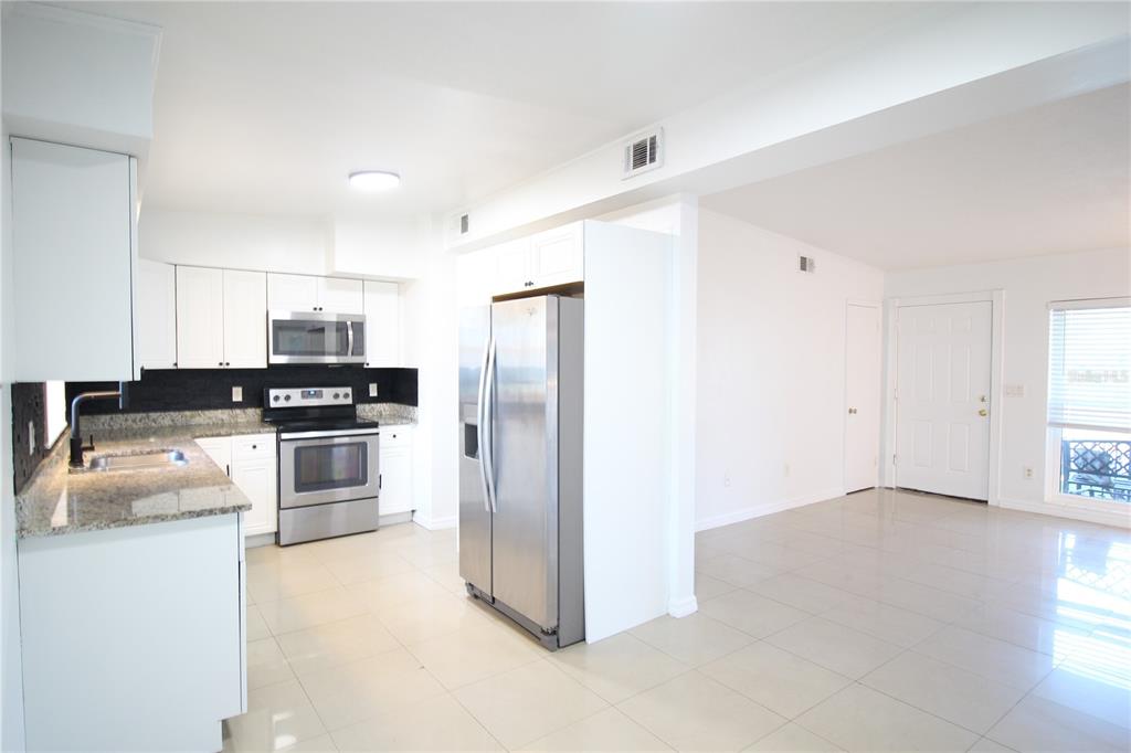 5910 Indian Hill Road Orlando, FL 32808 - Photo 3 of 12 a kitchen with granite countertop a refrigerator and a stove top oven