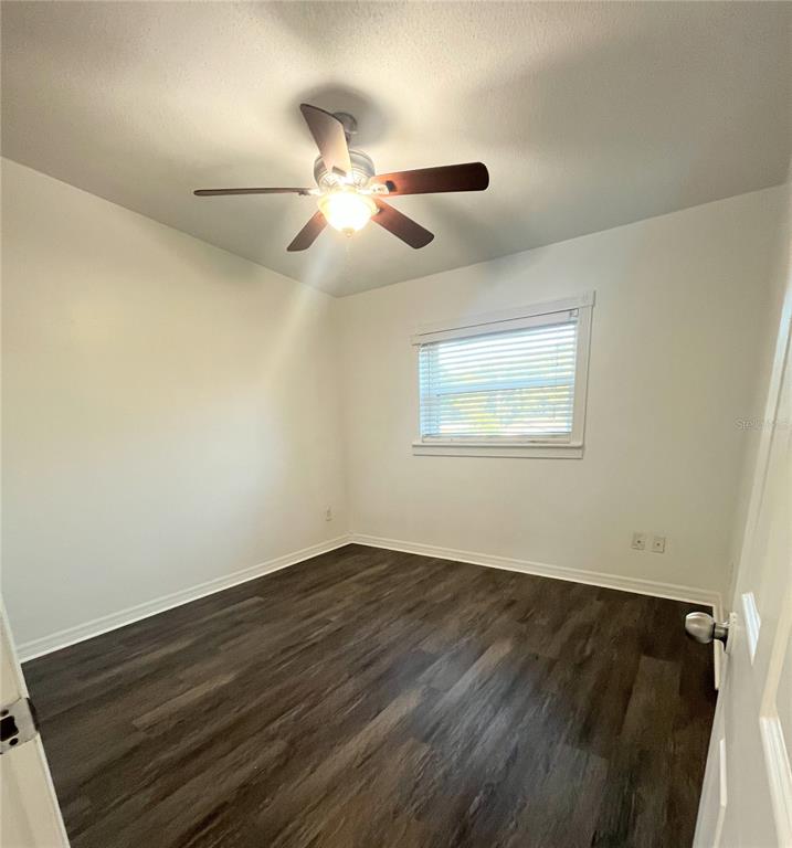 5910 Indian Hill Road Orlando, FL 32808 - Photo 6 of 12 an empty room with wooden floor fan and windows