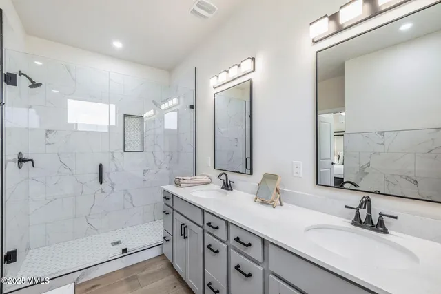 a bathroom with a double vanity sink mirror and shower