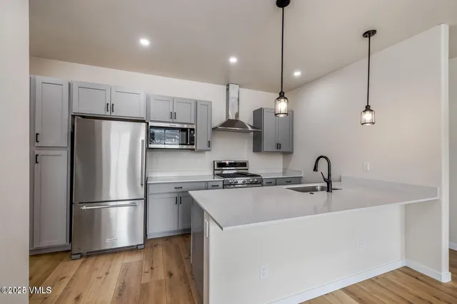 a kitchen with stainless steel appliances granite countertop a sink a refrigerator a stove a microwave and a sink with wooden floor